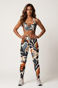 Woman wearing a colorful sports bra and leggings set on a white background