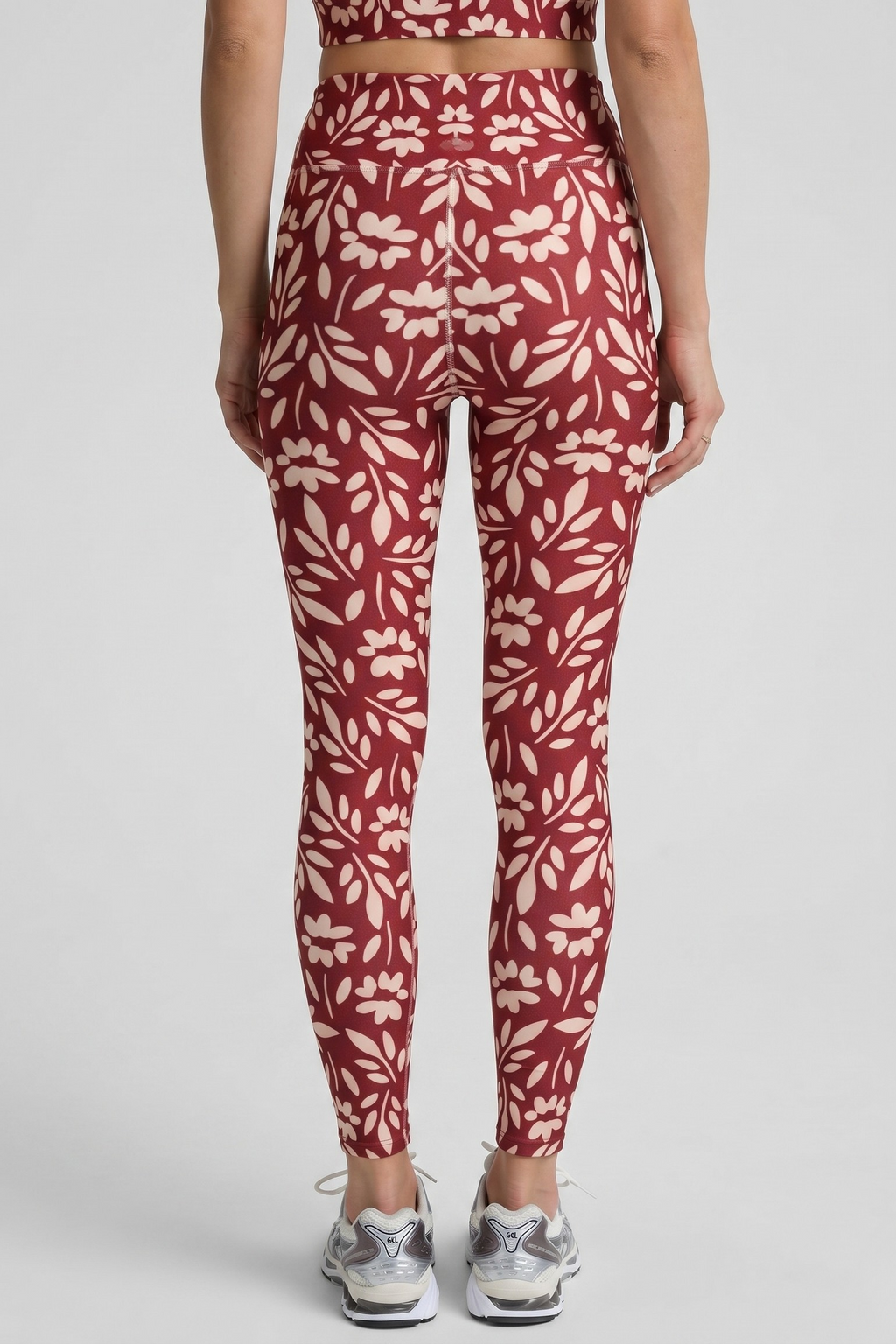 Person wearing red and white floral leggings on a light gray background