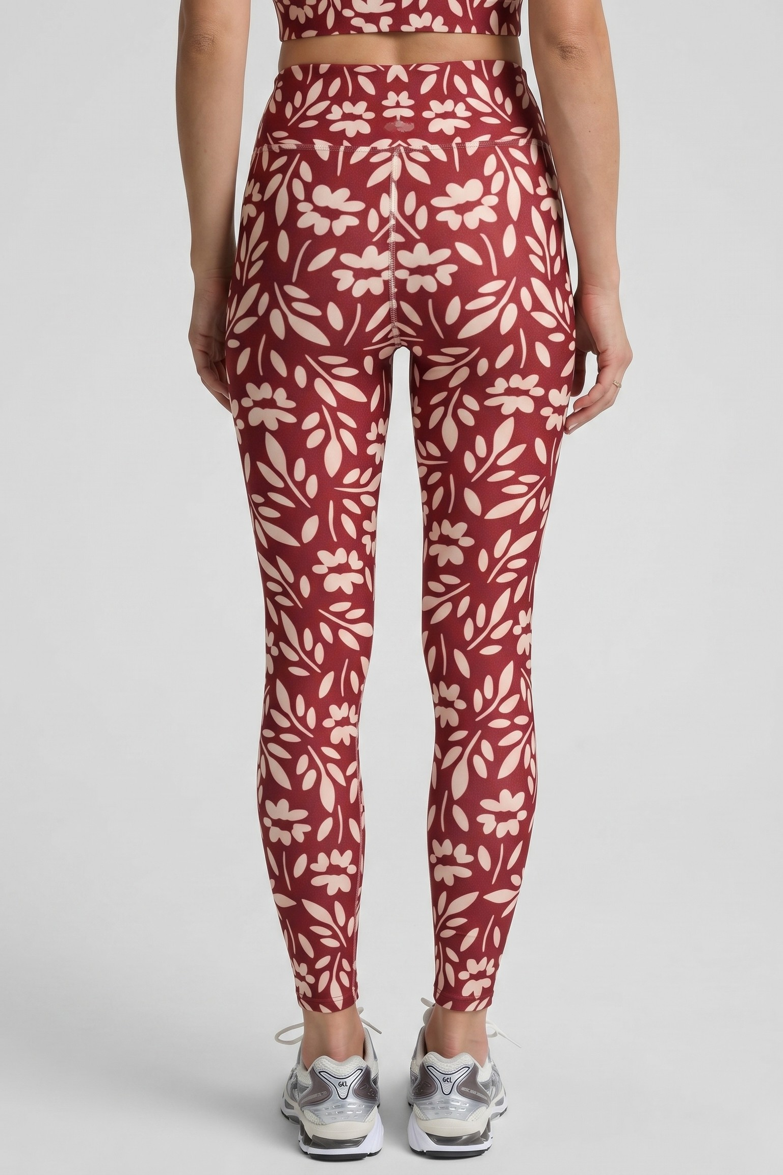 Person wearing red and white floral leggings on a light gray background