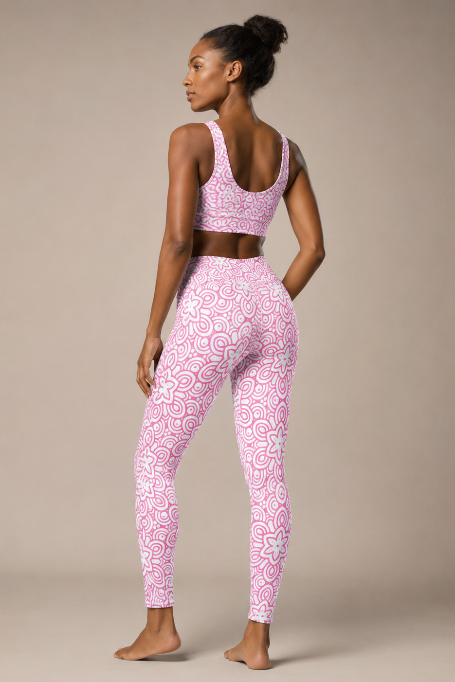 Woman wearing a pink patterned sports bra and leggings on a beige background