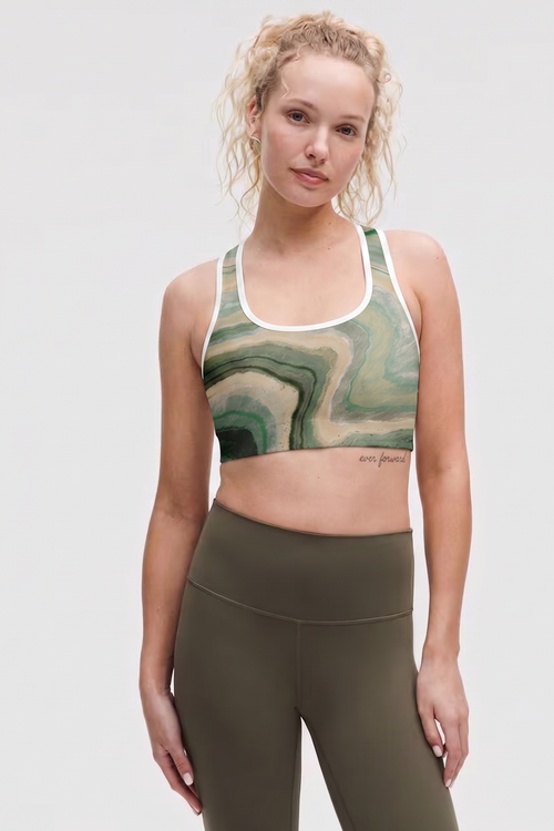 Woman wearing a green marble-patterned sports bra and olive green leggings on a white background