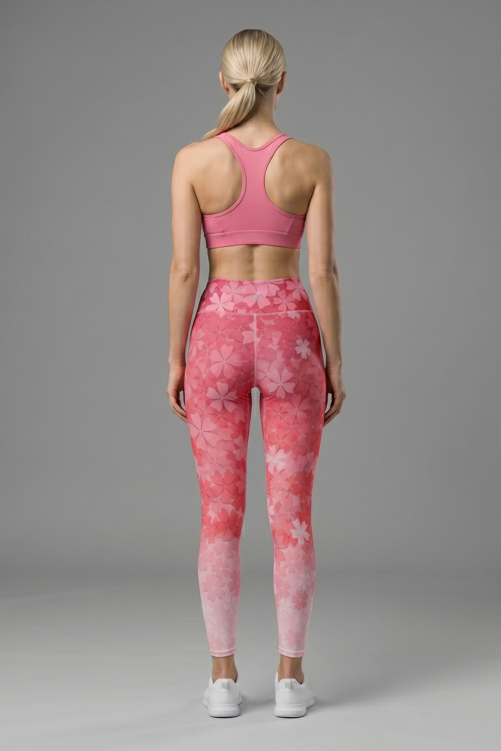 Woman wearing a pink sports bra and leggings with a gray background