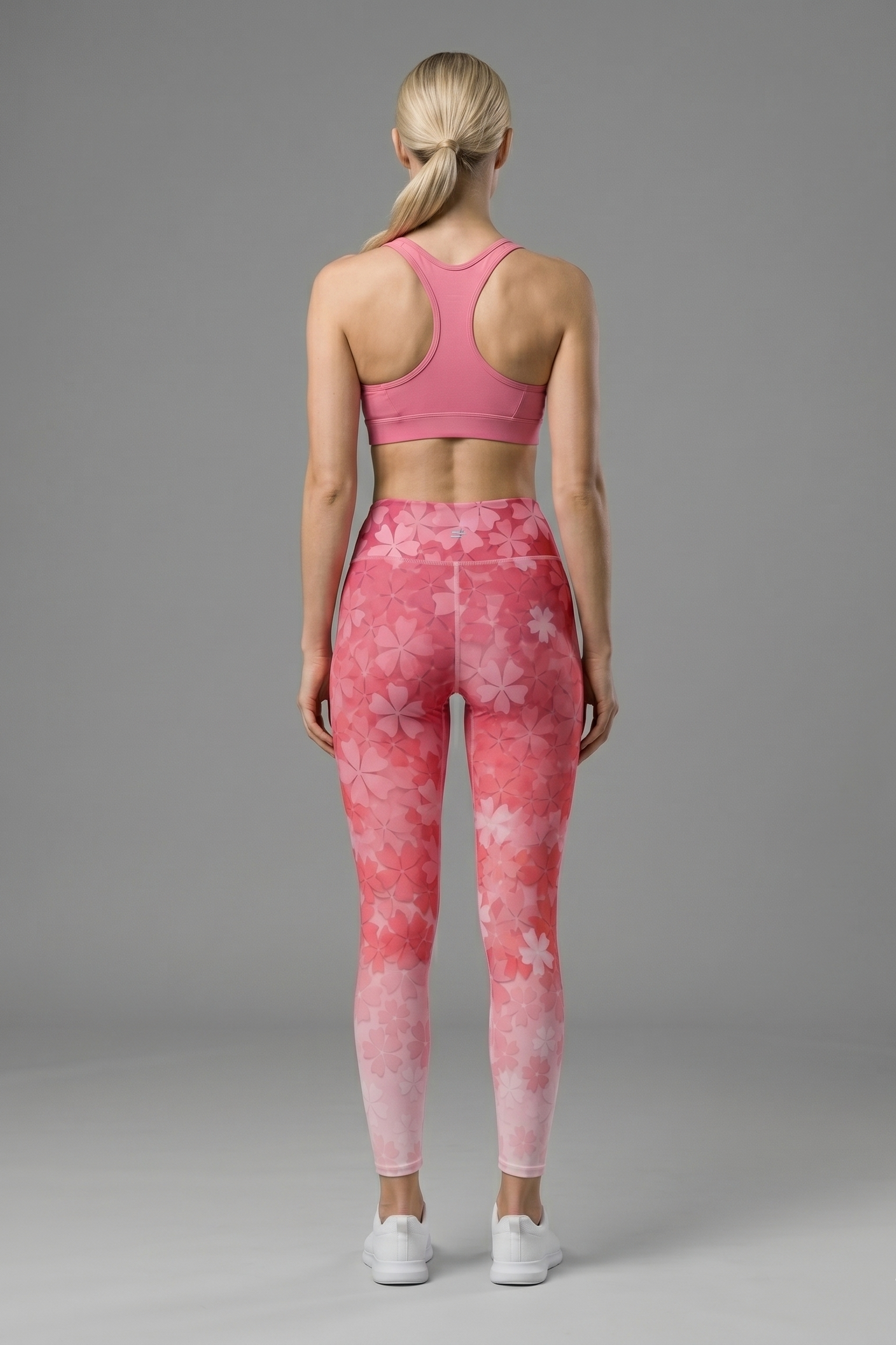 Woman wearing a pink sports bra and leggings with a gray background