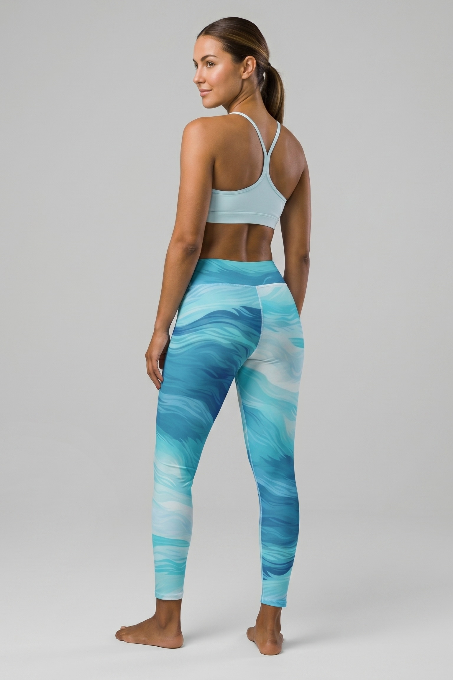 Woman wearing blue patterned leggings and light blue sports bra on a gray background