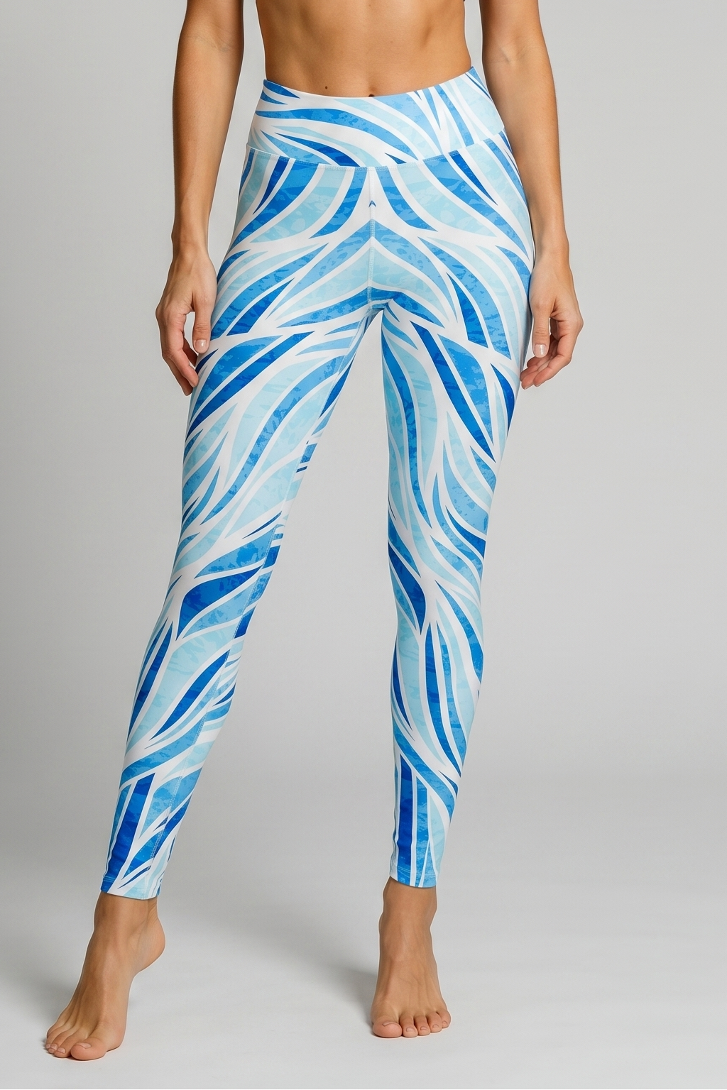 Woman wearing blue and white patterned leggings with a gray sports bra on a gray background