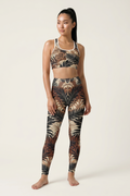 Woman wearing a leopard print sports bra and leggings set on a white background
