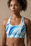 Woman wearing a blue and white patterned sports bra against a beige background