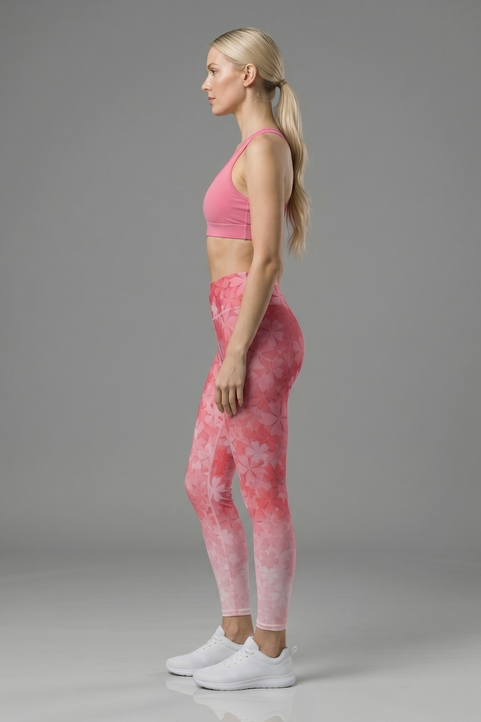 Woman wearing pink athletic top and leggings on a gray background