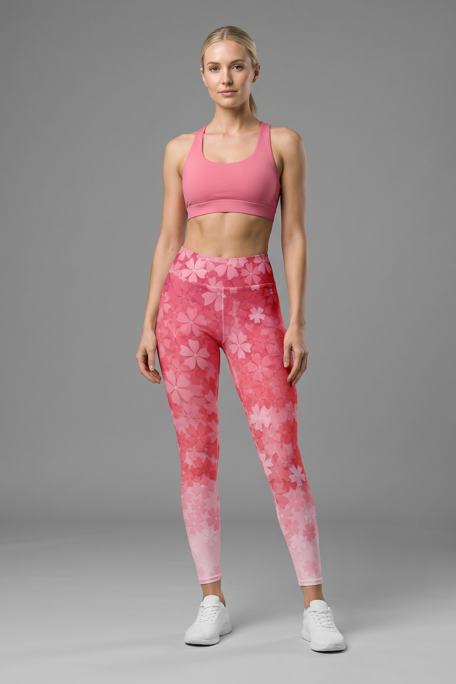 Woman wearing pink sports bra and leggings with floral pattern on a gray background