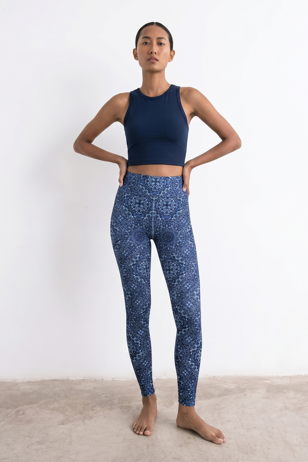 Woman wearing a navy blue athletic top and patterned leggings on a white background
