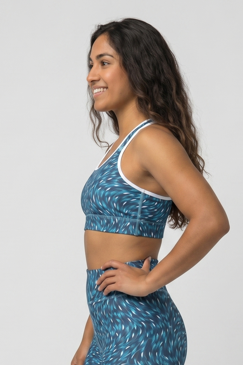 Woman wearing a blue patterned sports bra and leggings on a white background