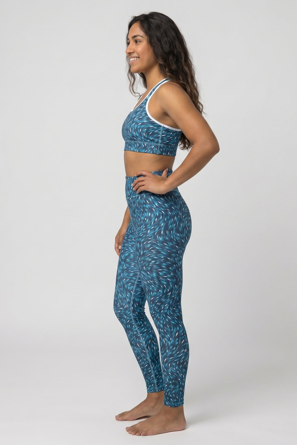 Woman wearing a blue patterned sports bra and leggings on a white background