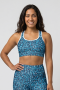 Woman wearing a blue patterned sports bra and leggings on a white background