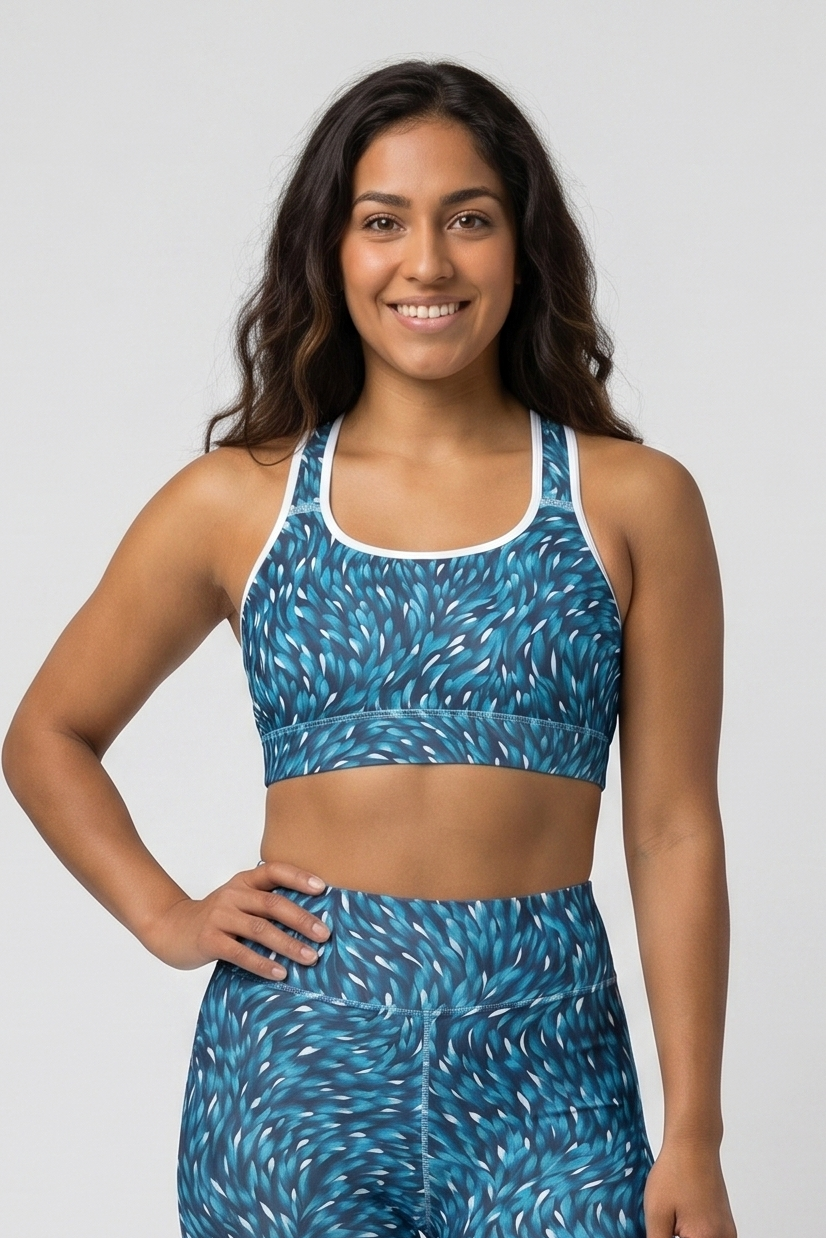 Woman wearing a blue patterned sports bra and leggings on a white background
