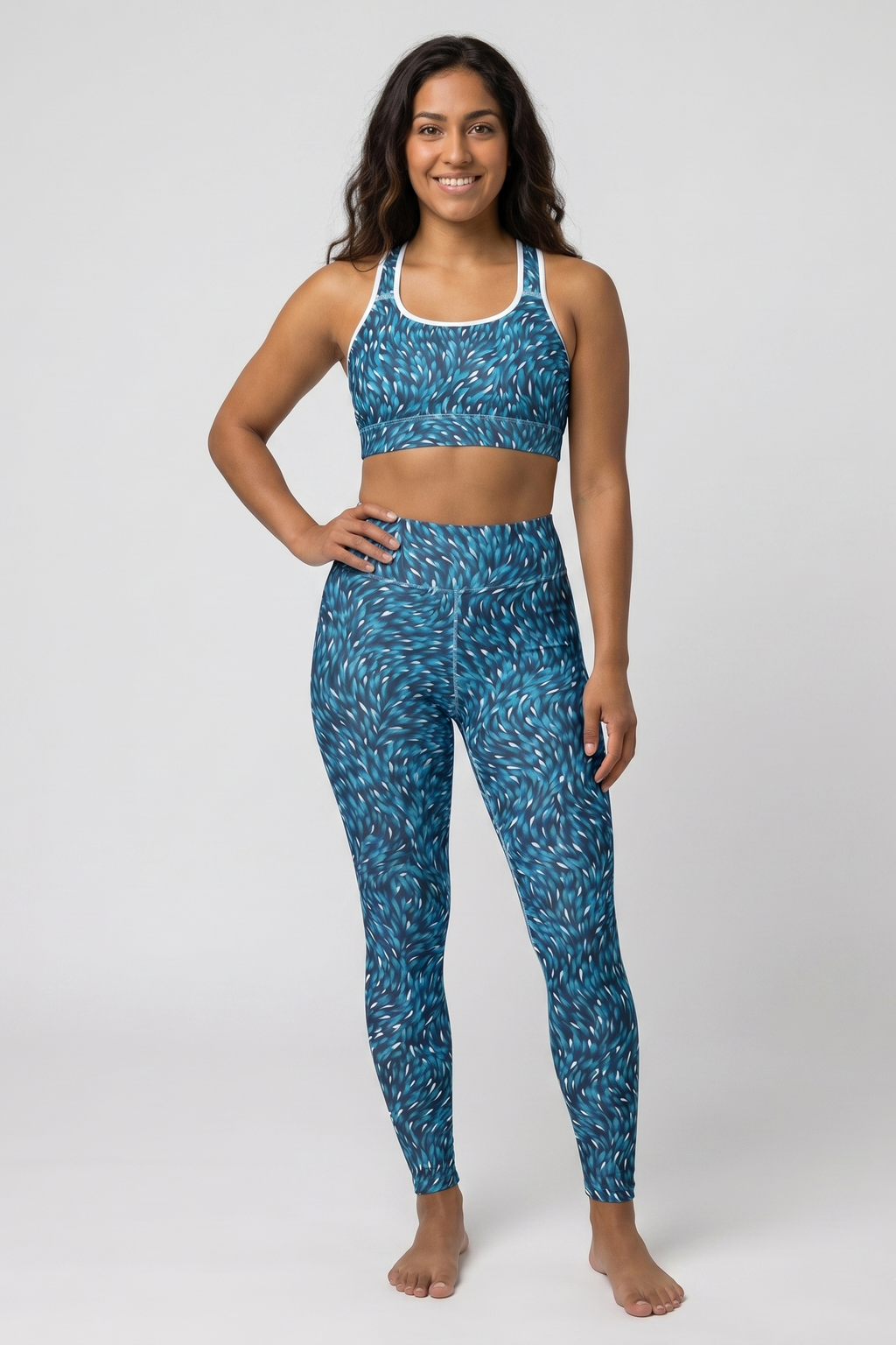Woman wearing a blue patterned sports bra and leggings on a white background