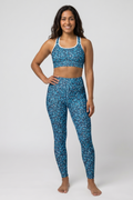 Woman wearing a blue patterned sports bra and leggings on a white background