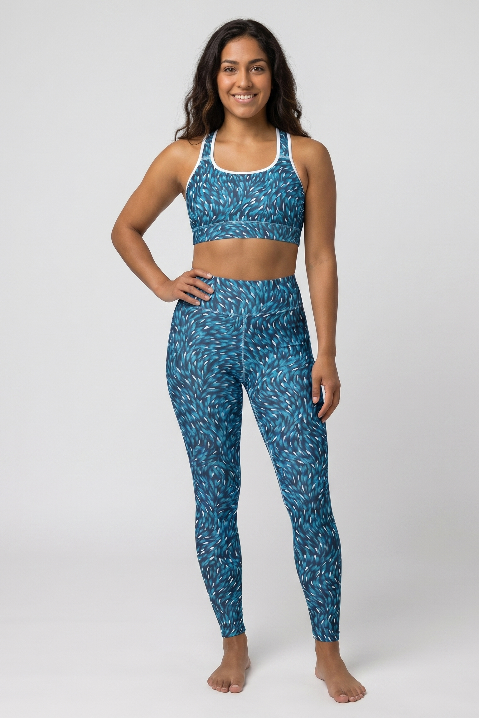 Woman wearing a blue patterned sports bra and leggings on a white background