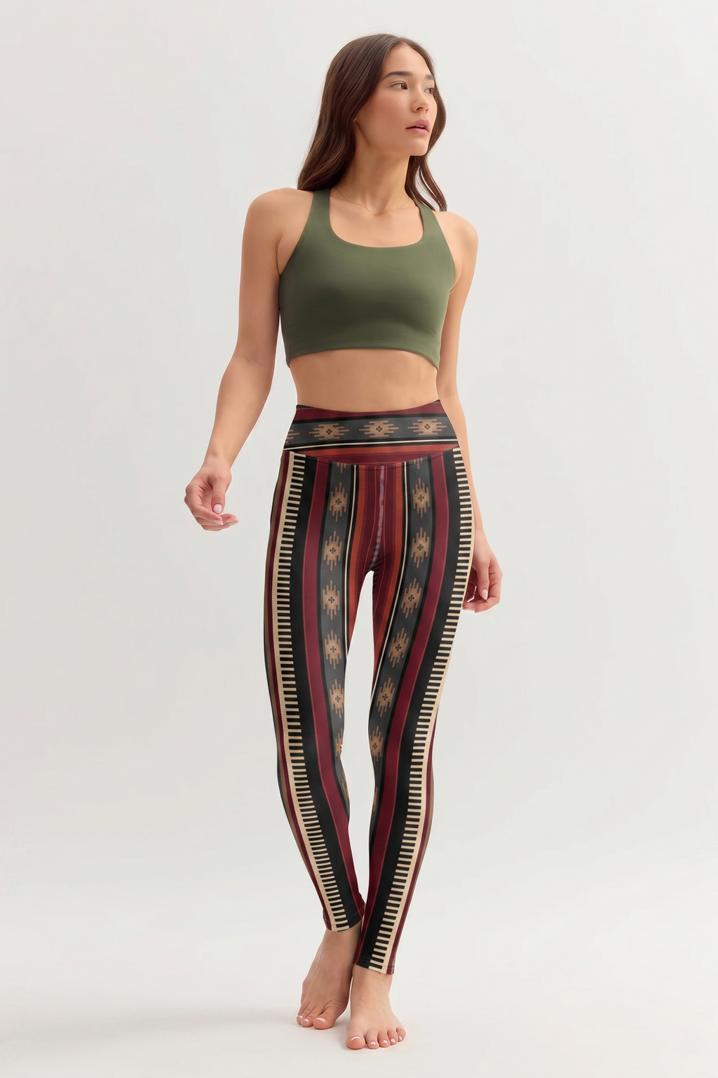 Woman wearing a green sports bra and patterned leggings on a white background