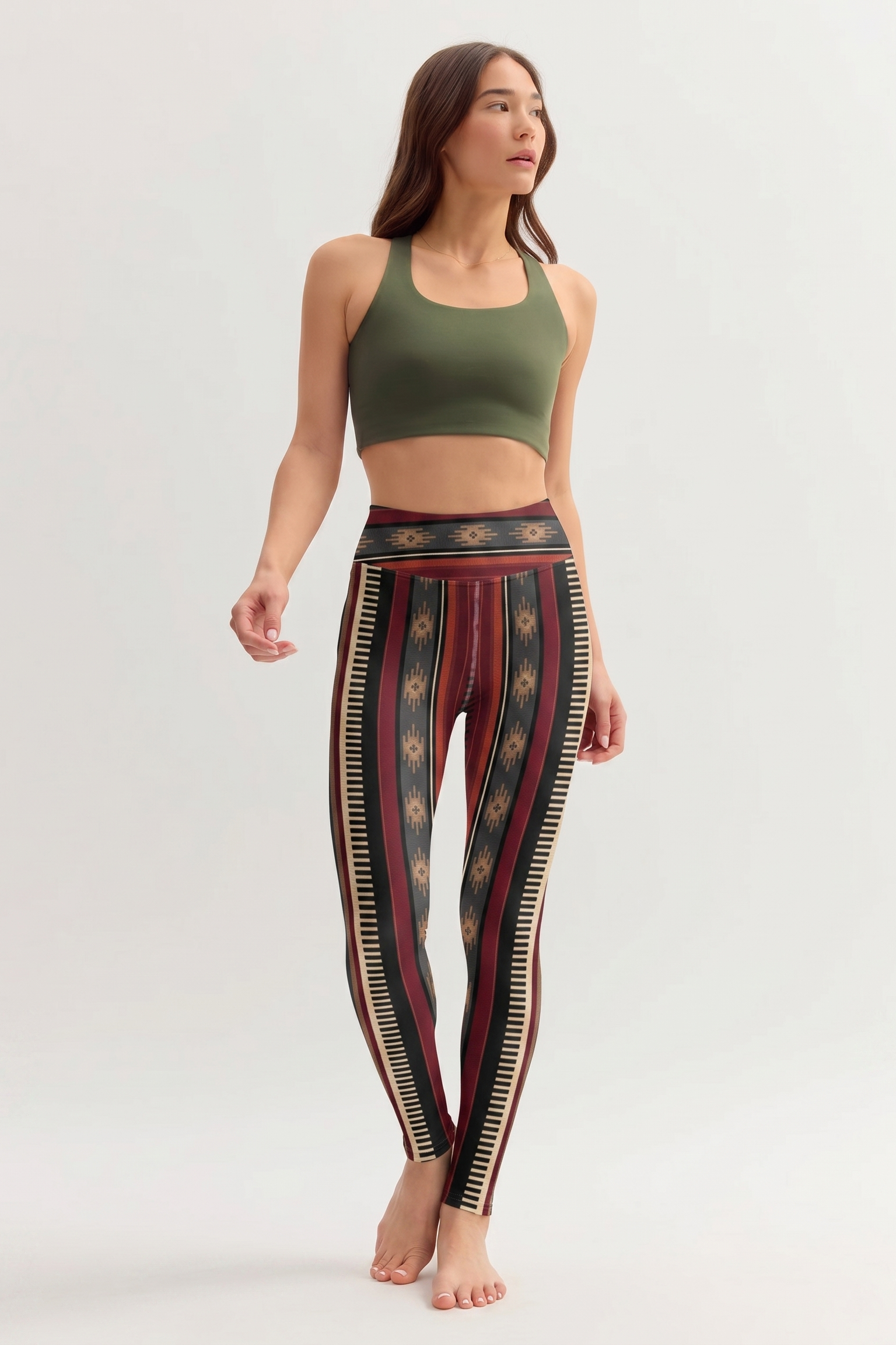 Woman wearing a green sports bra and patterned leggings on a white background