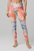 Woman wearing a colorful sports bra and leggings set on a gray background