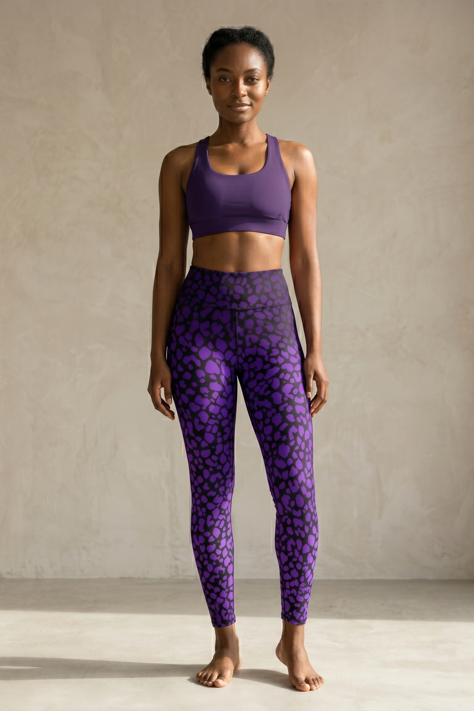 Woman wearing a purple sports bra and leggings with a pattern against a neutral background