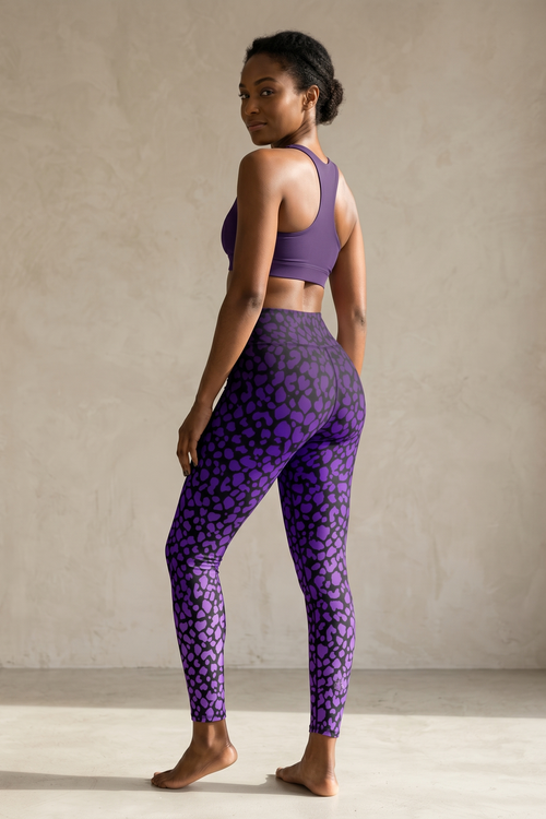 Woman wearing purple patterned leggings and sports bra against a neutral background