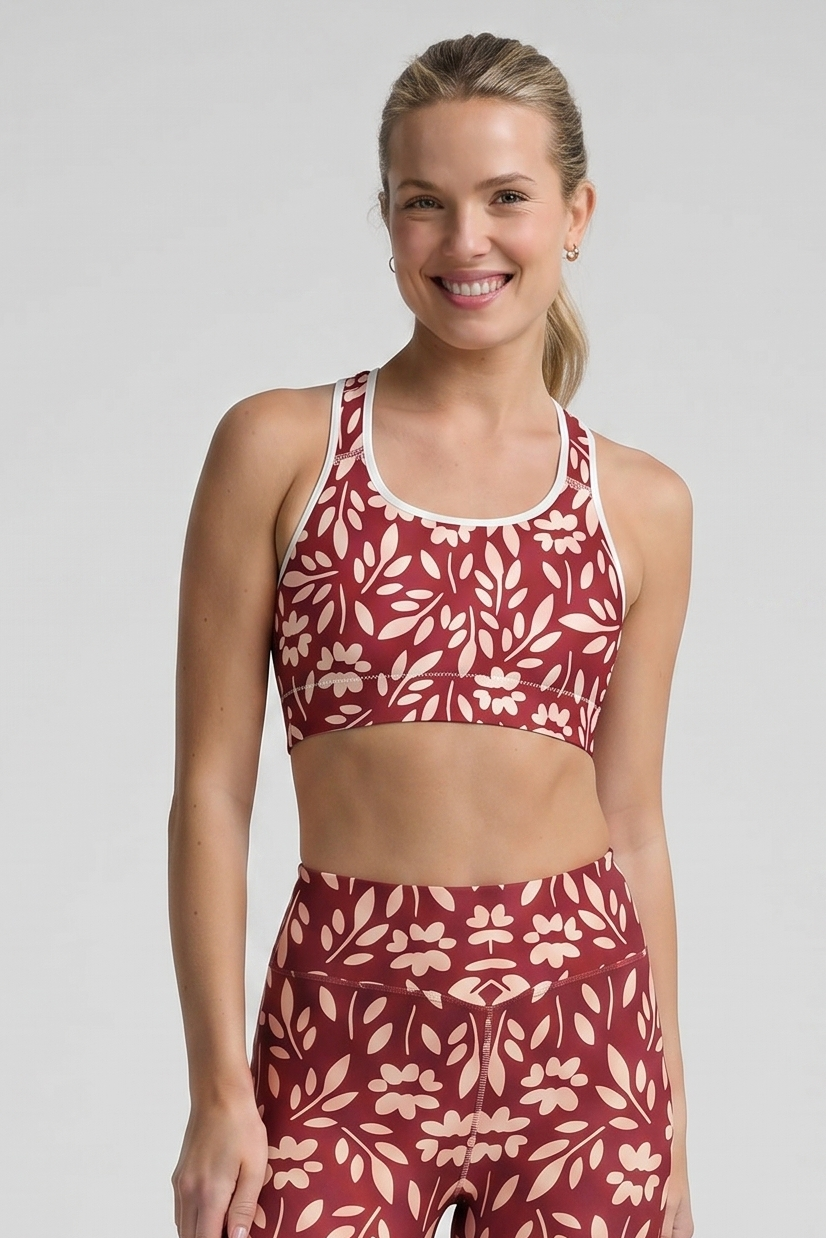 Woman wearing a red and white patterned sports bra and leggings set on a gray background