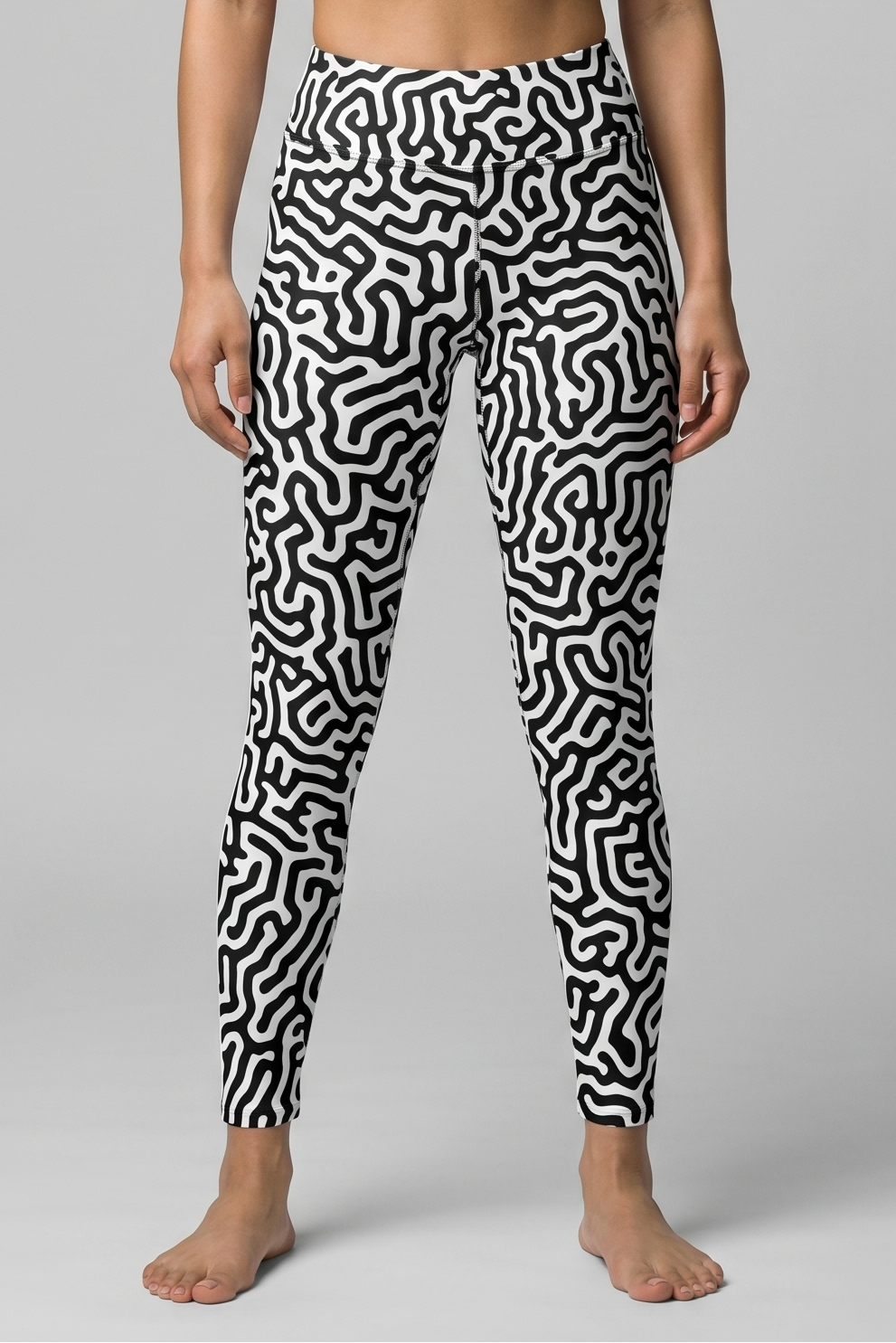 Woman wearing a black and white patterned sports bra and leggings on a gray background