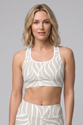 Woman wearing a white and beige patterned athletic outfit on a gray background