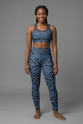Woman wearing a blue patterned sports bra and leggings set on a gray background