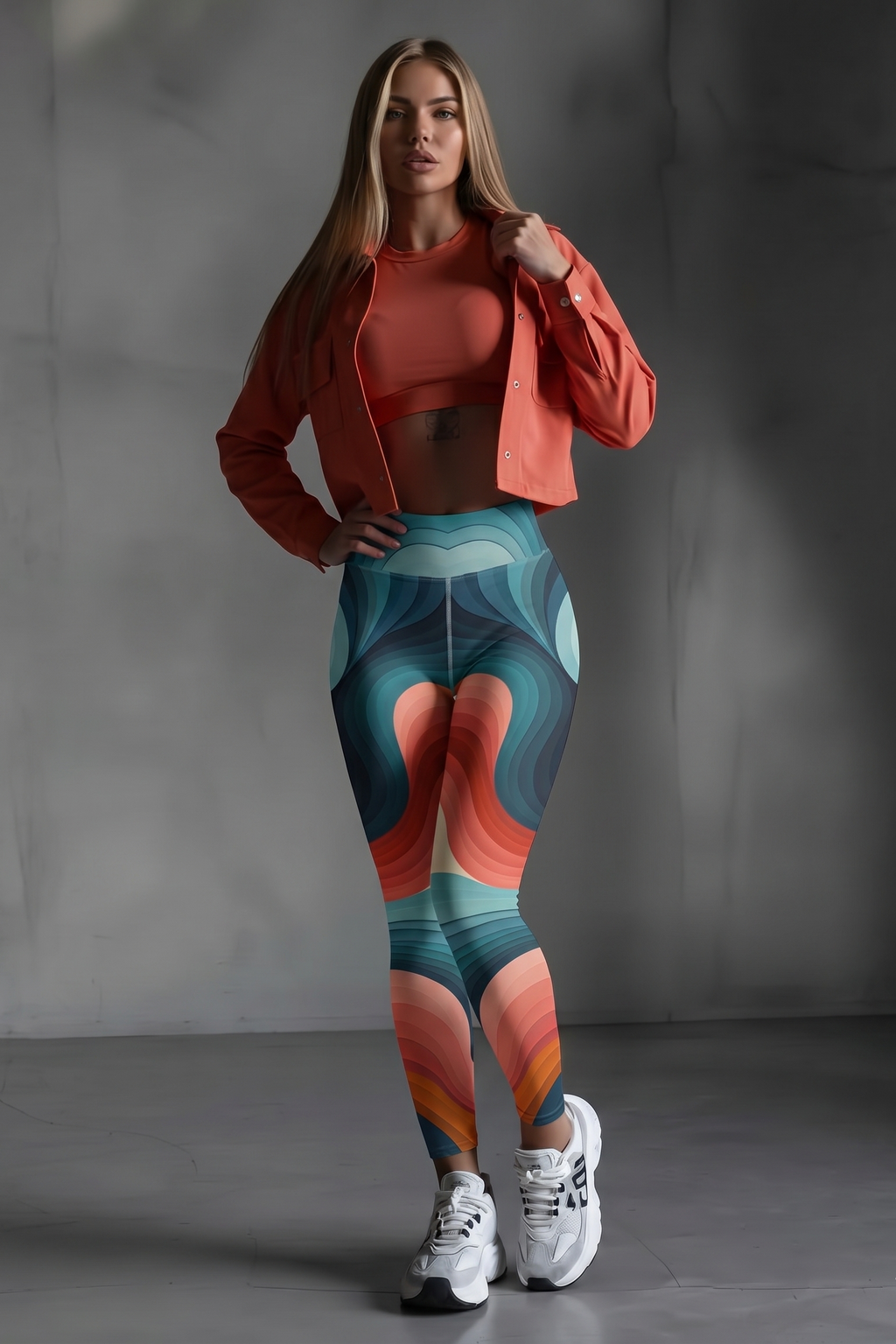 Woman wearing a colorful patterned leggings and coral jacket against a gray background