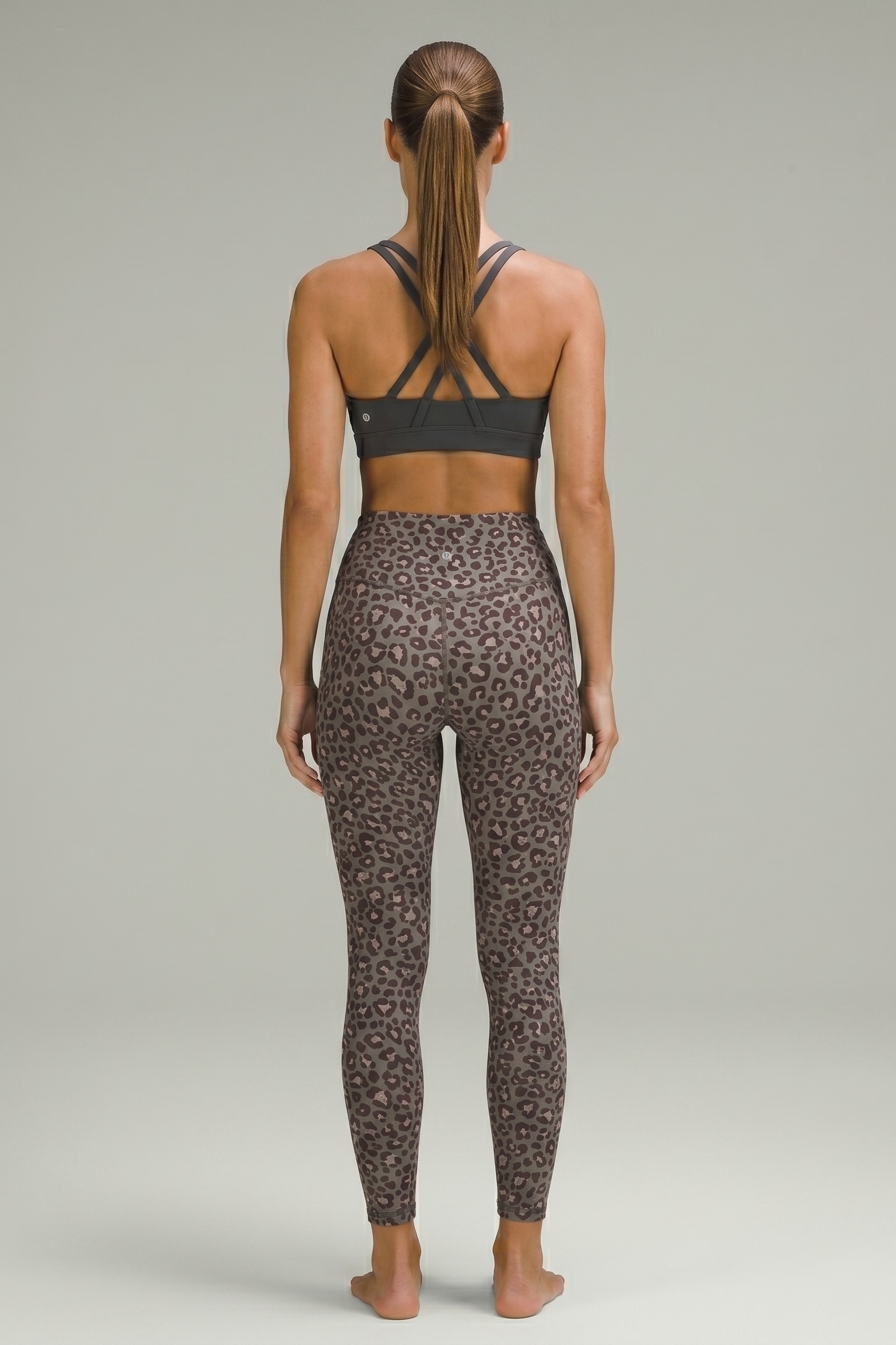 Person wearing a black sports bra and leopard print leggings on a gray background