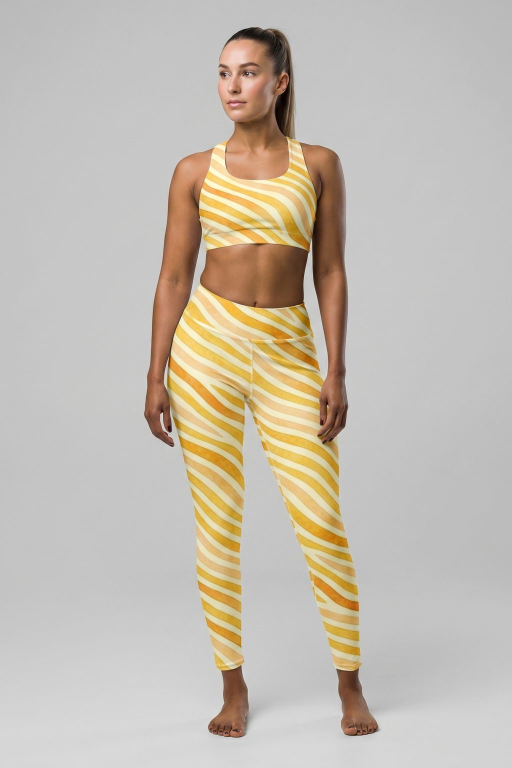Woman wearing a yellow and white striped sports bra and leggings set on a gray background