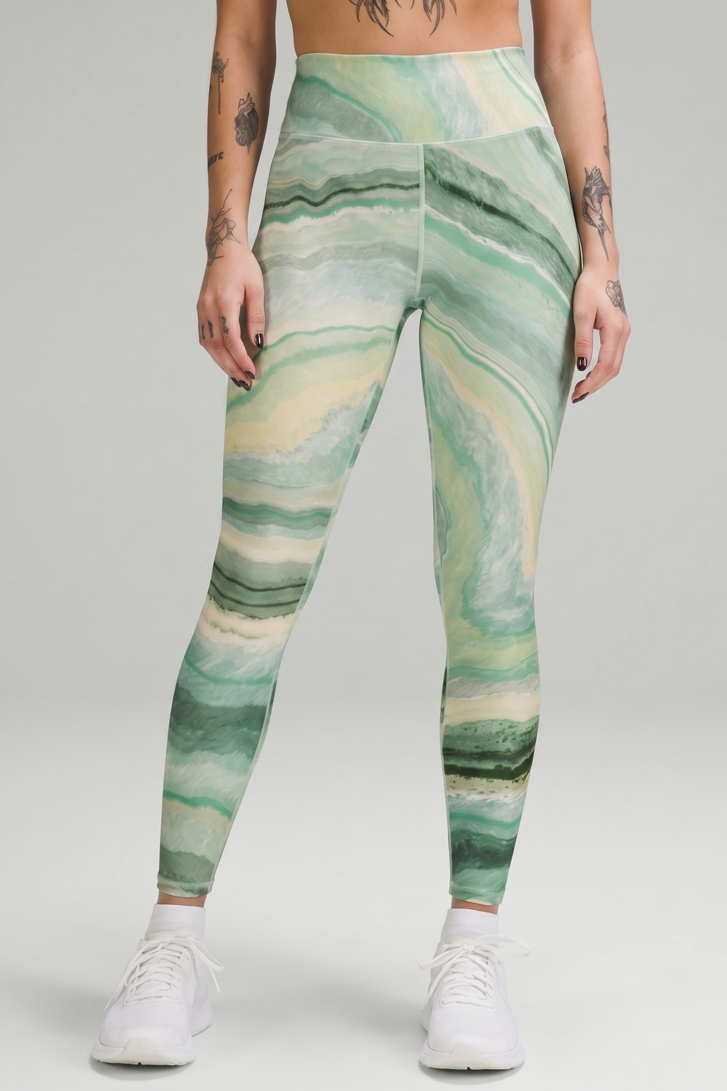 Person wearing green marble pattern leggings on a gray background