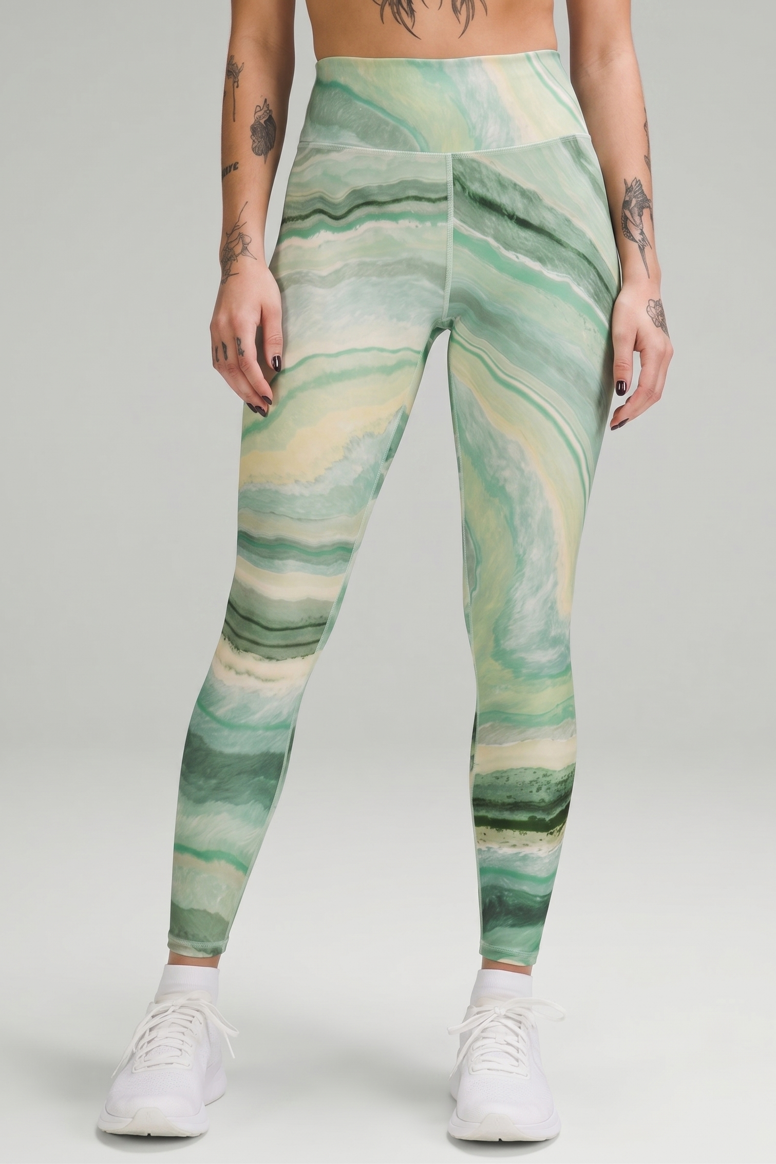 Person wearing green marble pattern leggings on a gray background