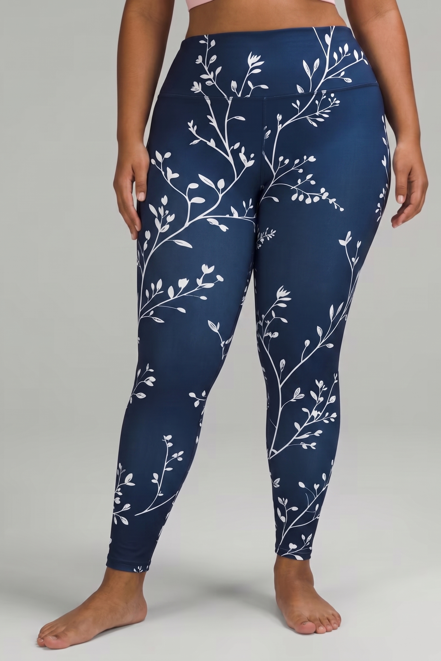 Navy blue leggings with white floral pattern worn by a person on a gray background