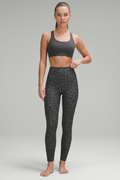 Woman wearing a black sports bra and patterned leggings on a gray background