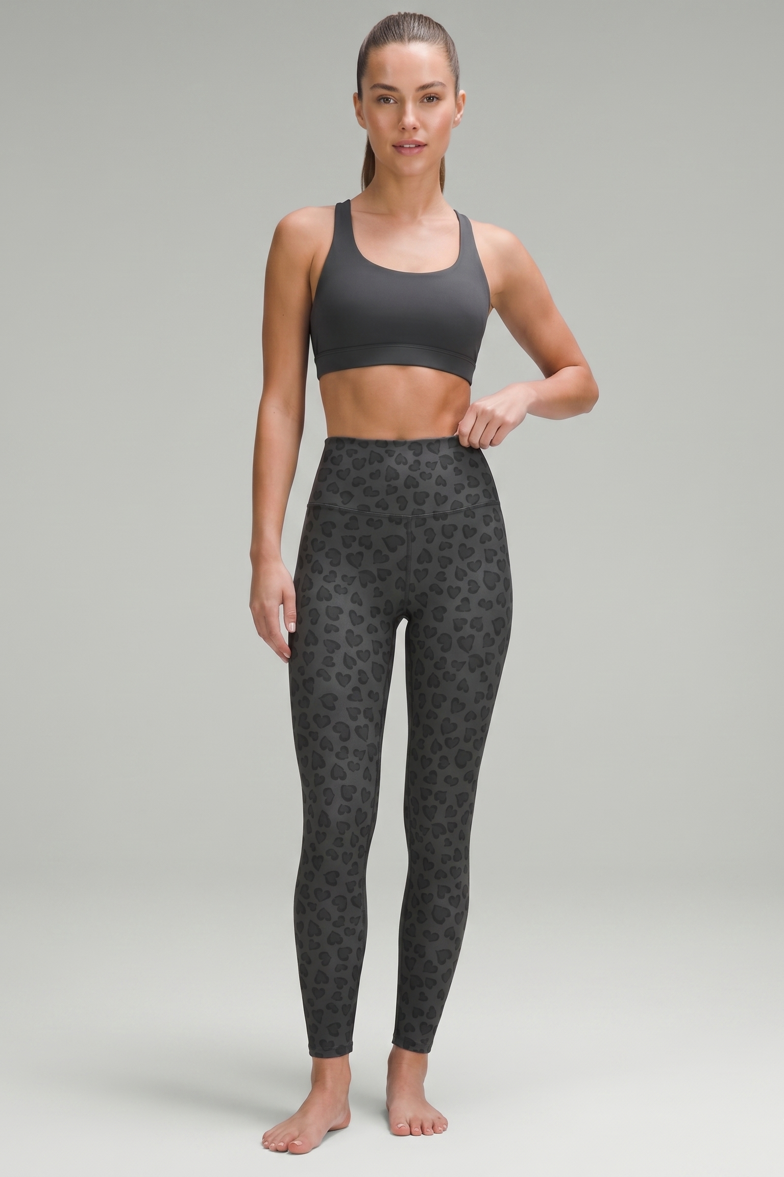 Woman wearing a black sports bra and patterned leggings on a gray background