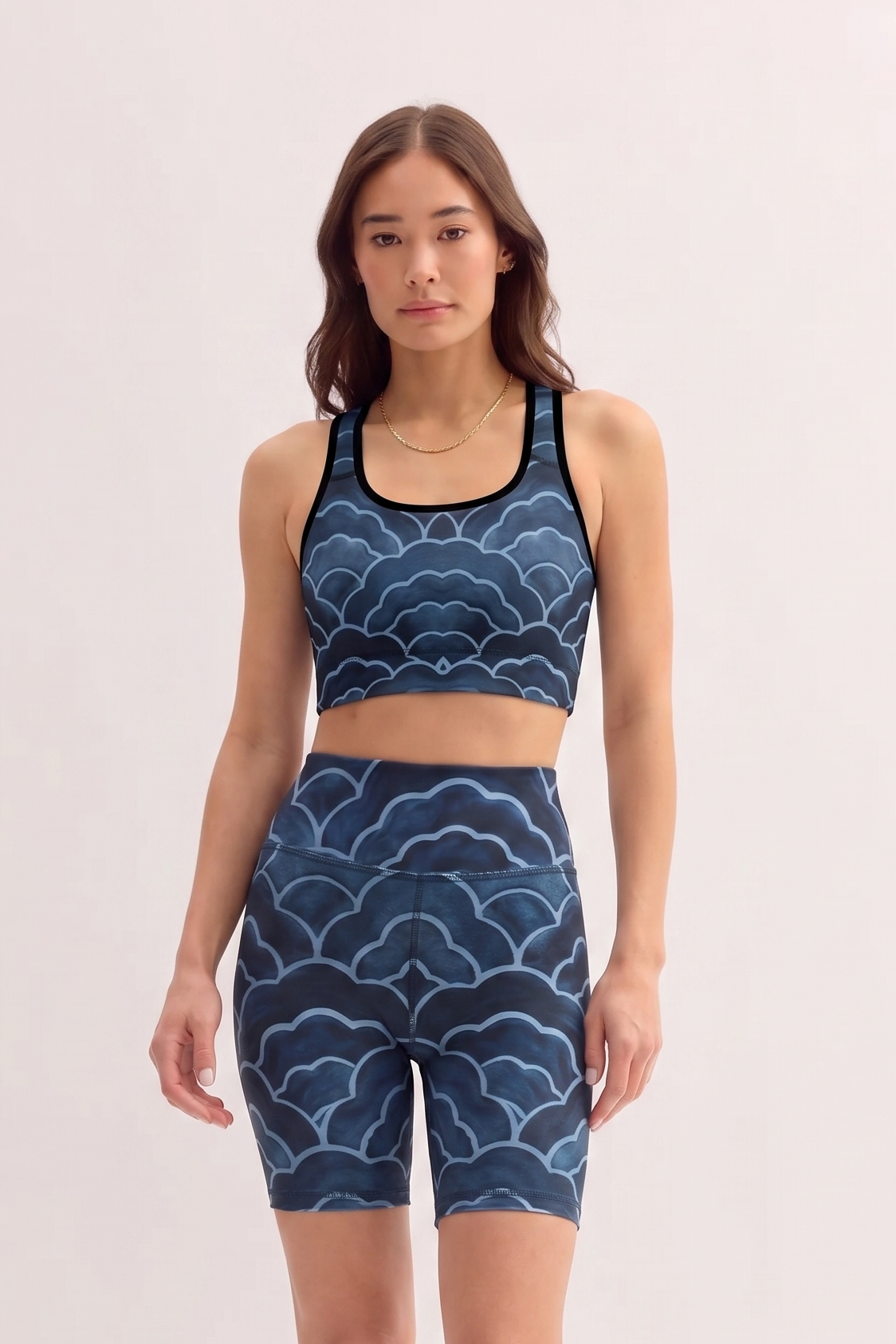 Woman wearing a blue patterned sports bra and shorts set on a light pink background